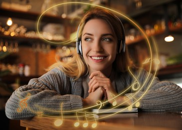 Image of Woman with headphones at table in cafe. Music notes flying around her