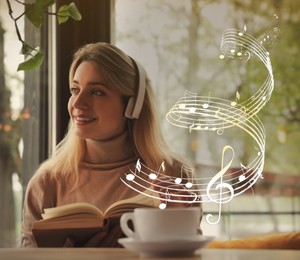 Image of Woman with headphones and book at table in cafe. Music notes flying near her