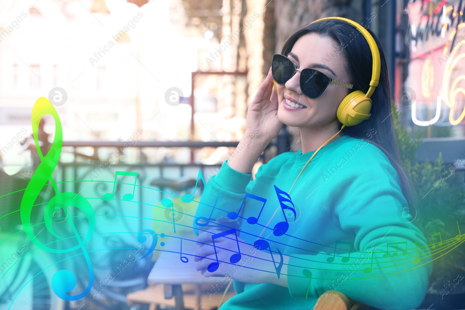 Image of Happy young woman with coffee and headphones outdoors. Music notes flying near her