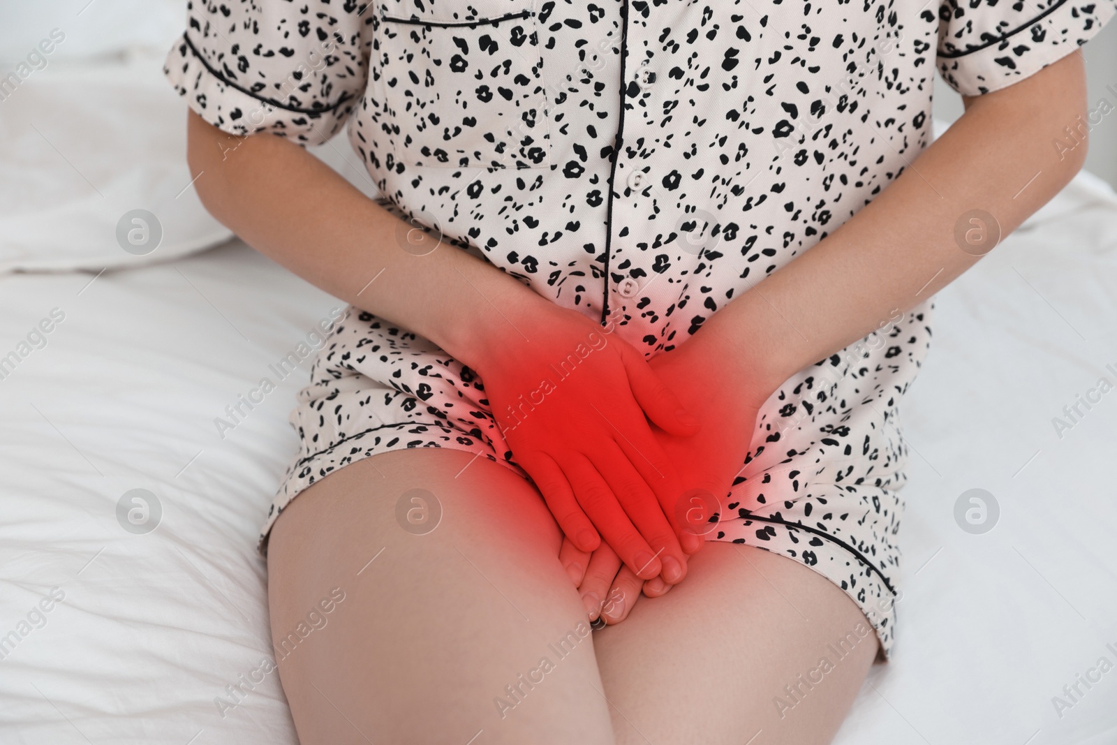 Image of STD (sexually transmitted diseases). Woman holding hands near her groin on bed, closeup