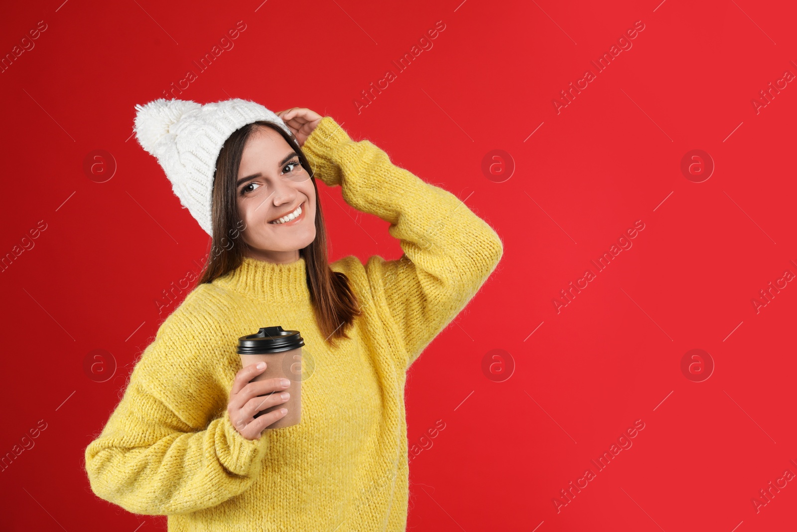 Photo of Happy beautiful woman with paper cup of mulled wine on red background. Space for text