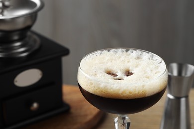 Photo of Delicious espresso martini with coffee beans in glass on blurred background, closeup