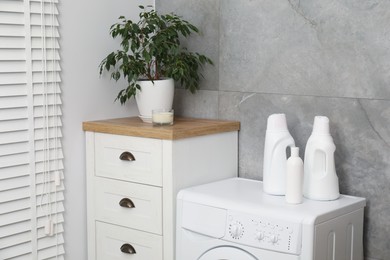 Photo of Laundry detergents in bottles and washing machine indoors