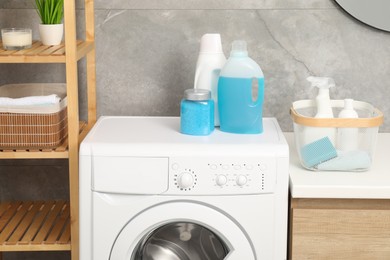 Photo of Different laundry detergents and washing machine in bathroom