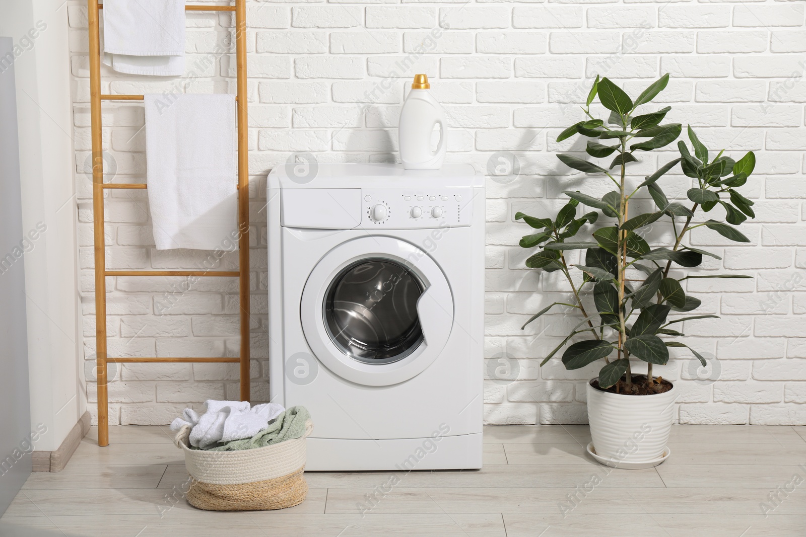 Photo of Detergent, washing machine and basket full of laundry in bathroom