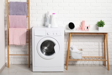 Photo of Laundry detergents, washing machine and clean towels in bathroom