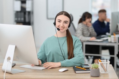 Photo of Saleswoman talking to client via headset at desk in office