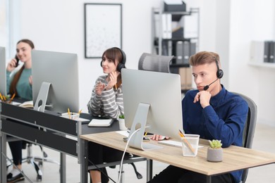 Photo of Sales department. People with headsets working in office, selective focus