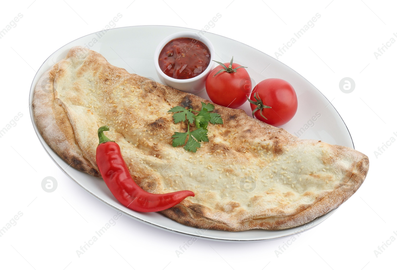 Photo of Delicious calzone with ketchup, fresh tomatoes and chili pepper isolated on white