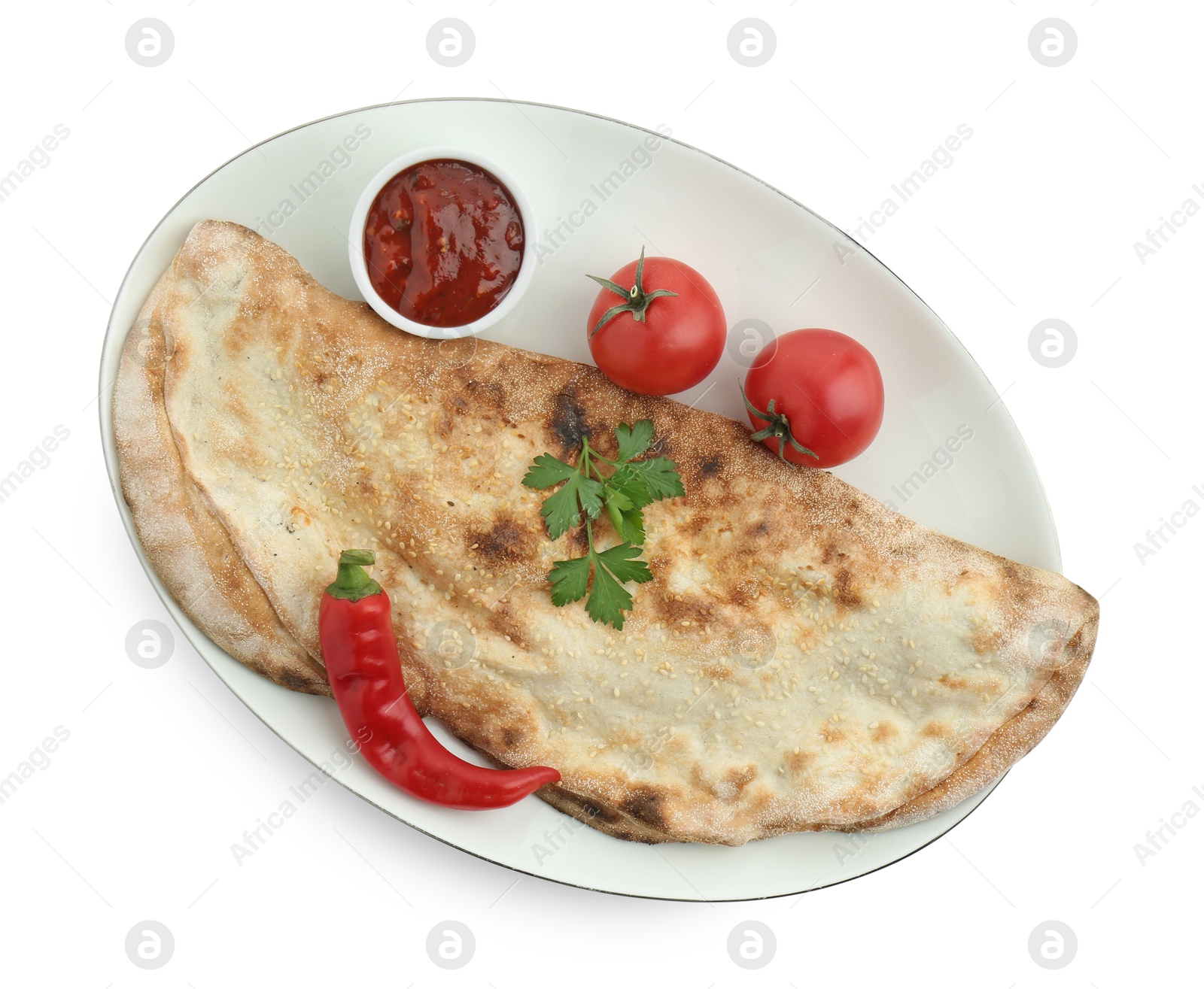 Photo of Delicious calzone with ketchup, fresh tomatoes and chili pepper isolated on white, top view