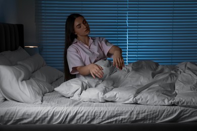 Photo of Young woman suffering from sleepwalking on bed at home