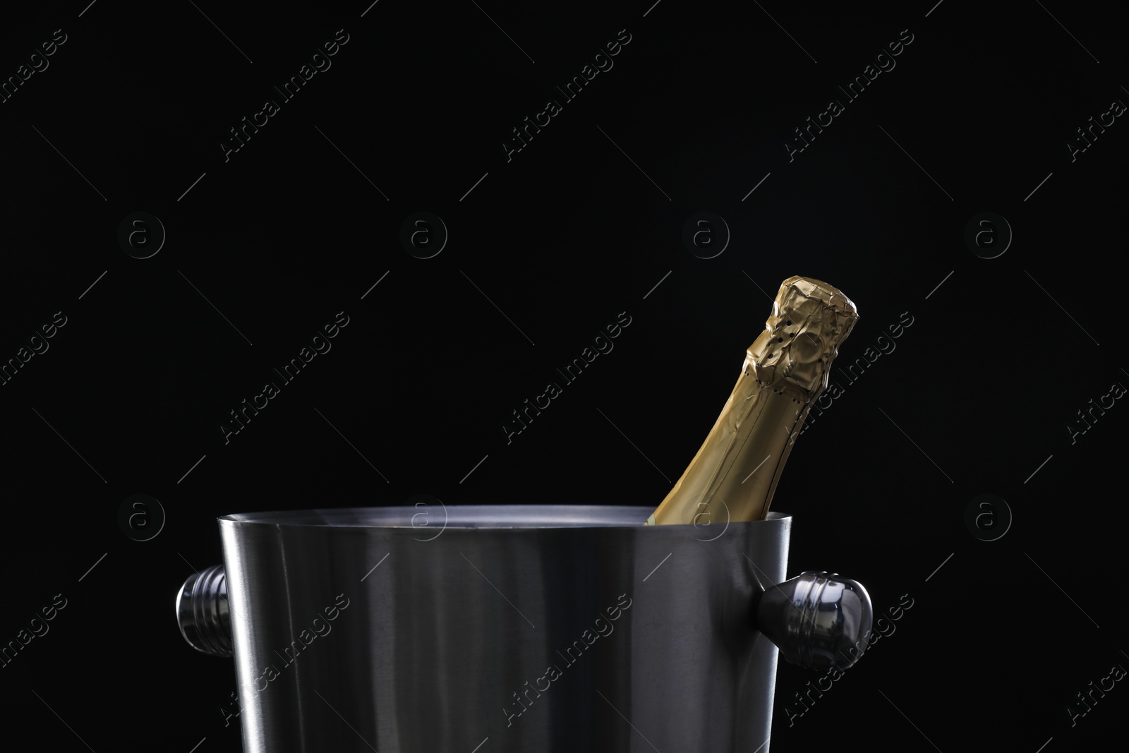 Photo of Bottle of champagne in bucket on black background