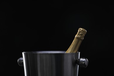 Photo of Bottle of champagne in bucket on black background