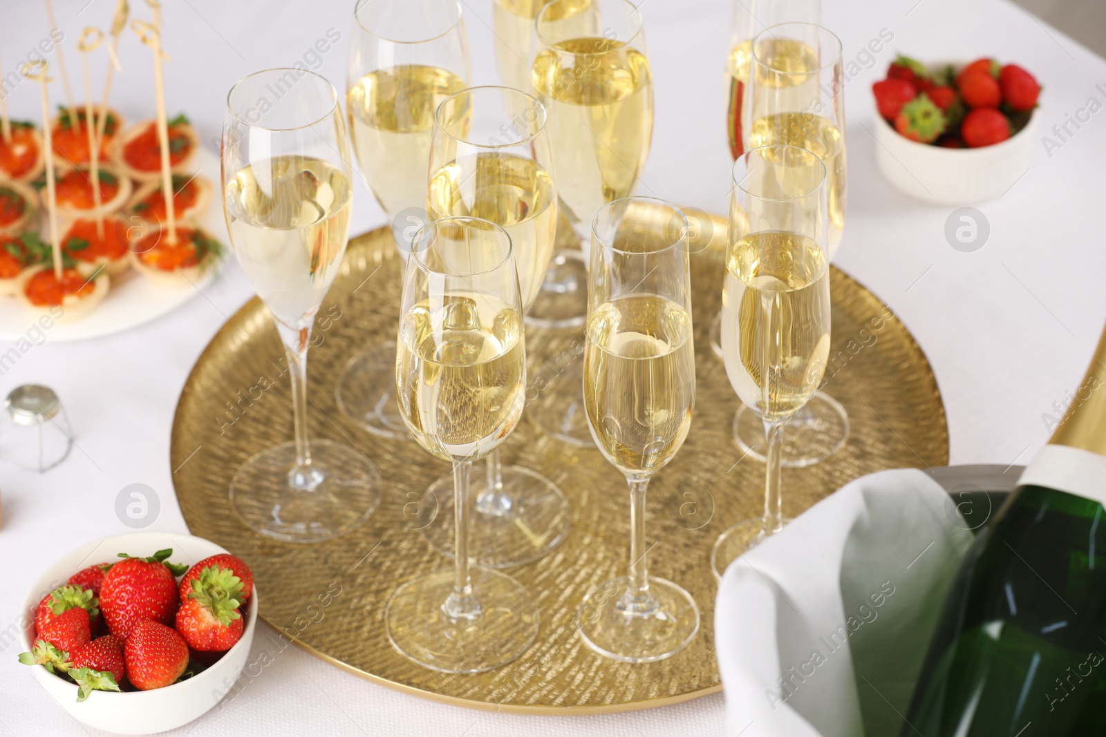 Photo of Champagne, strawberries and canapes with red caviar on white table