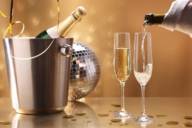 Photo of Pouring champagne into glass against golden background, closeup