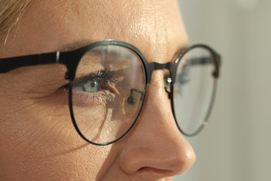 Photo of Woman wearing stylish glasses on blurred background, closeup