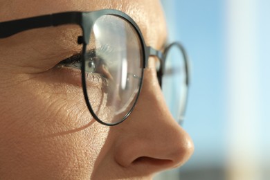 Photo of Woman wearing stylish glasses on blurred background, closeup