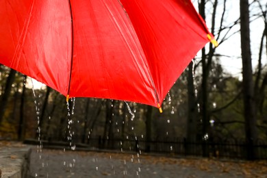 Photo of Open red umbrella under pouring rain outdoors, closeup