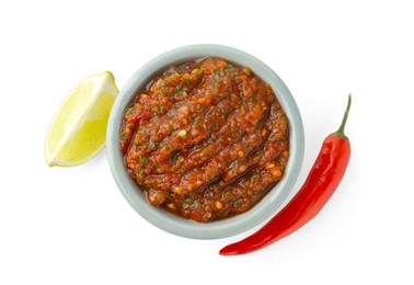 Photo of Tasty salsa sauce in bowl, lime and chili pepper isolated on white, top view