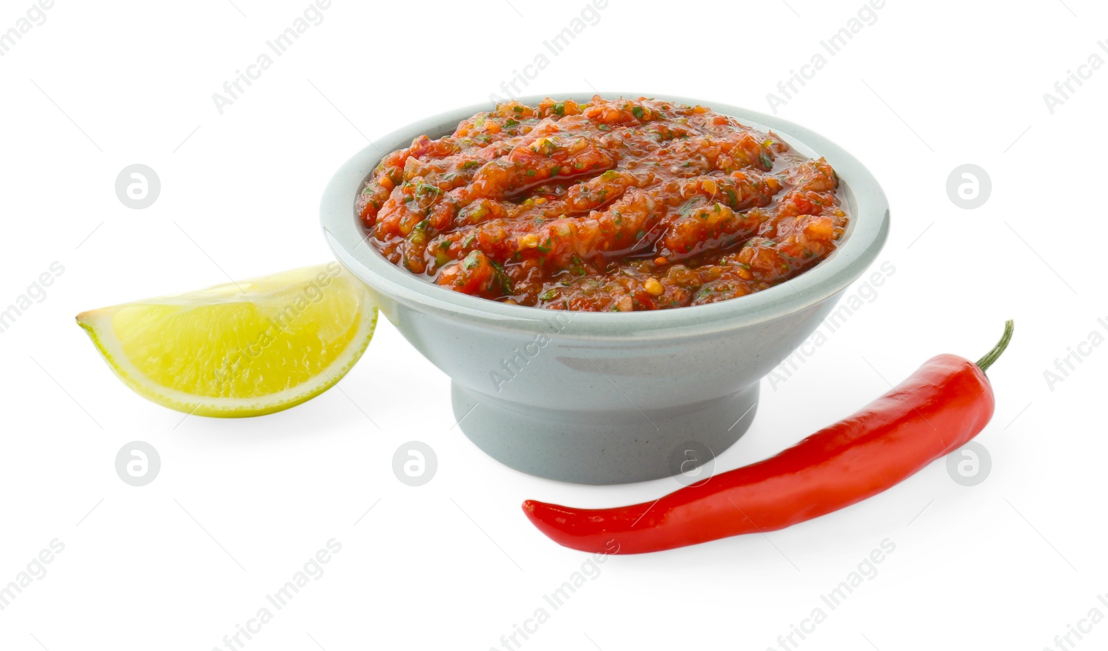 Photo of Tasty salsa sauce in bowl, lime and chili pepper isolated on white