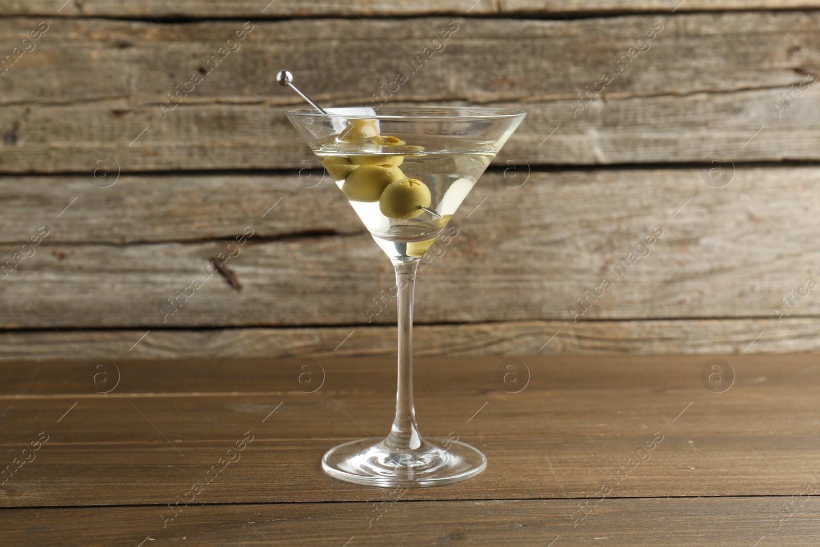 Photo of Martini cocktail with olives in glass on wooden table