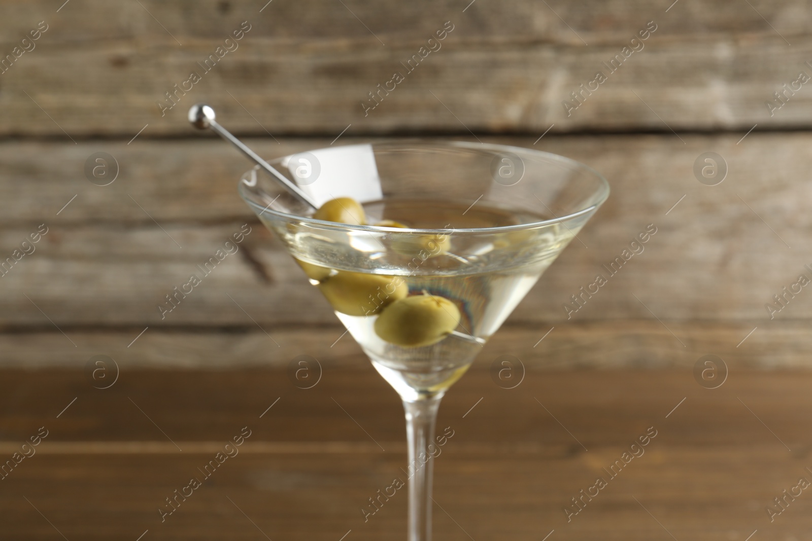 Photo of Martini cocktail with olives in glass on table, closeup