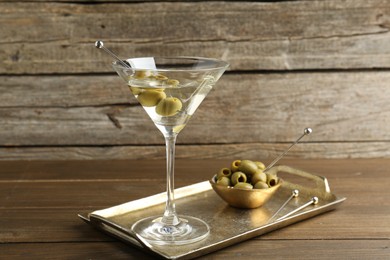 Photo of Martini cocktail in glass with olives on wooden table