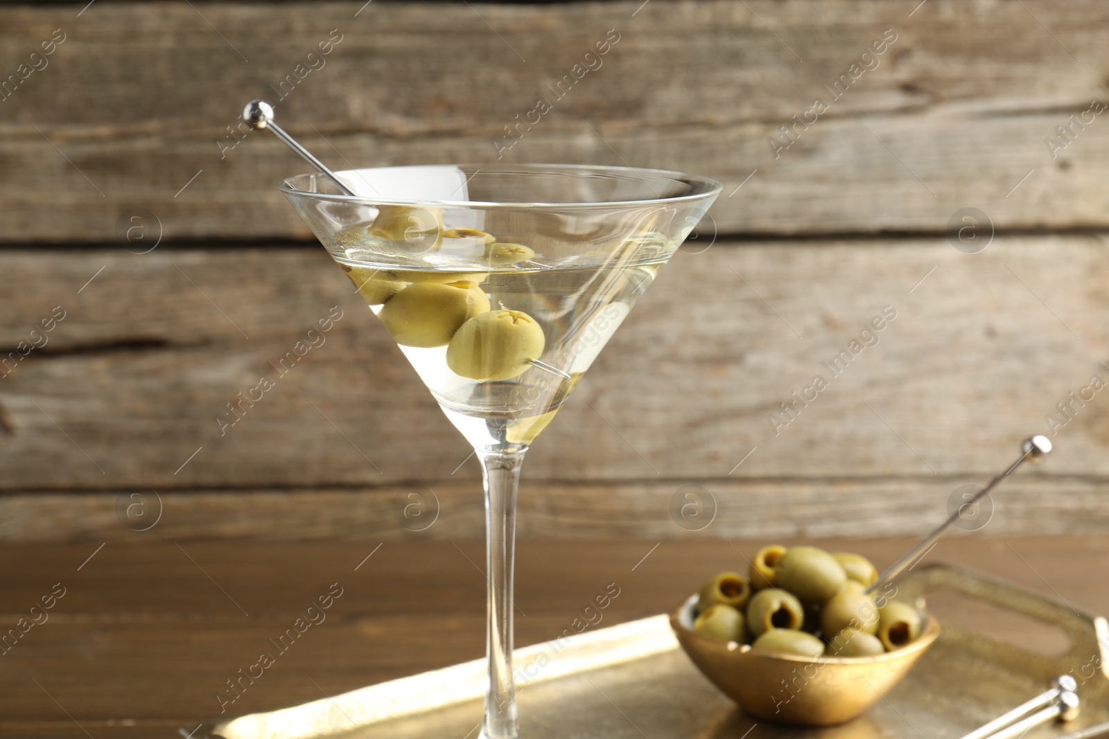 Photo of Martini cocktail in glass with olives on table