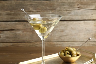 Martini cocktail in glass with olives on table