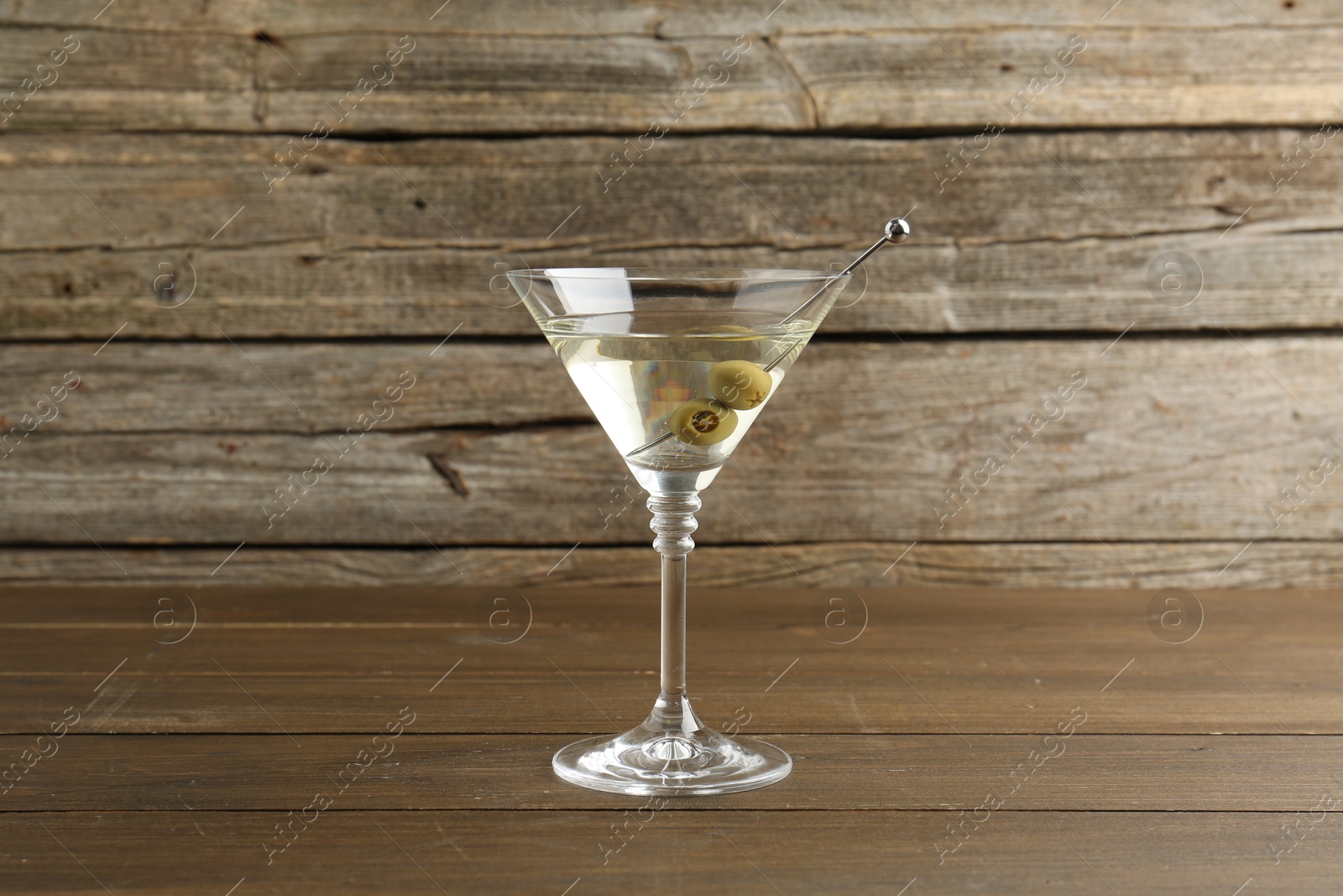 Photo of Martini cocktail with olives in glass on wooden table