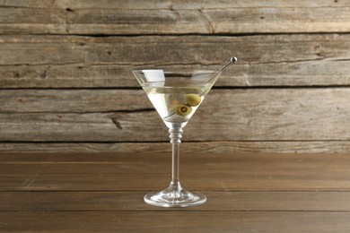 Photo of Martini cocktail with olives in glass on wooden table