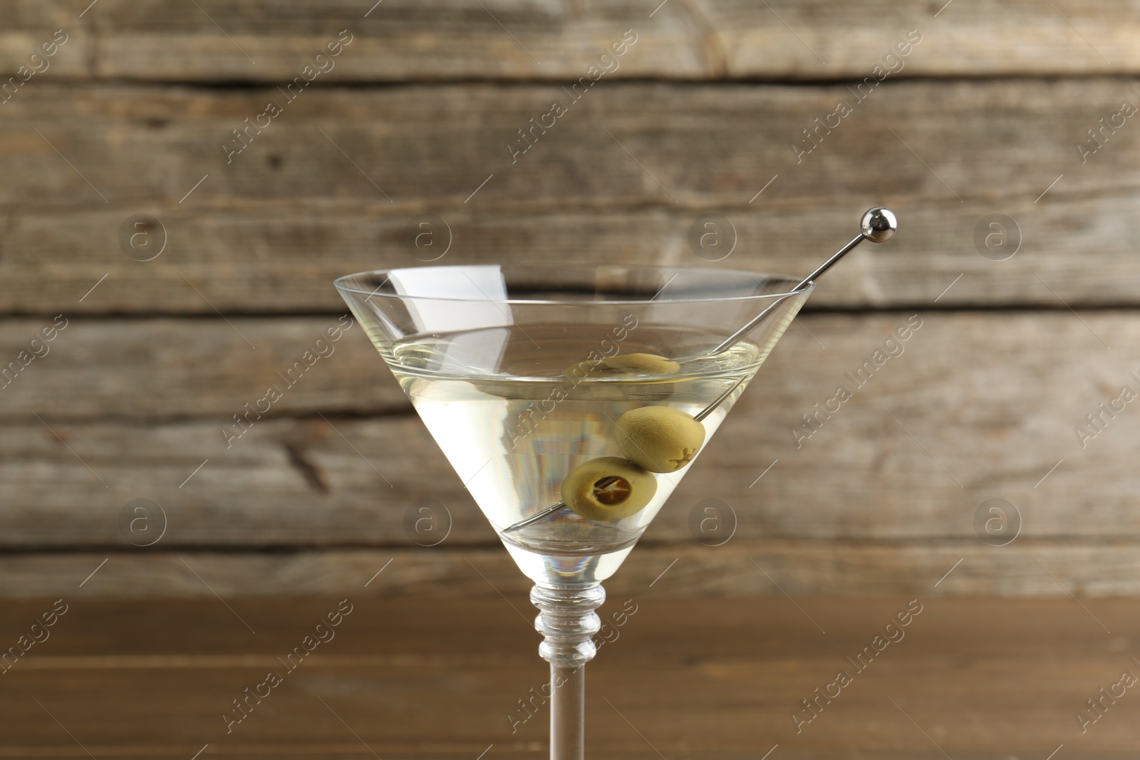 Photo of Martini cocktail with olives in glass on table, closeup