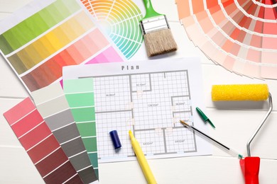 Photo of Designer's workplace with color palettes, floor plan and different supplies on white wooden table, flat lay