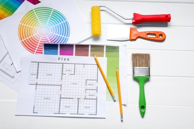 Photo of Designer's workplace with different color palettes, floor plans and pencil on white wooden table, flat lay