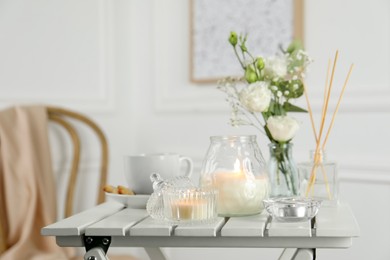 Photo of Beautiful burning candle, tea and flowers on white wooden table