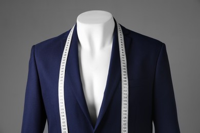 Photo of Male mannequin with blue jacket and measuring tape on grey background, closeup