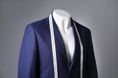 Photo of Male mannequin with blue jacket and measuring tape on grey background