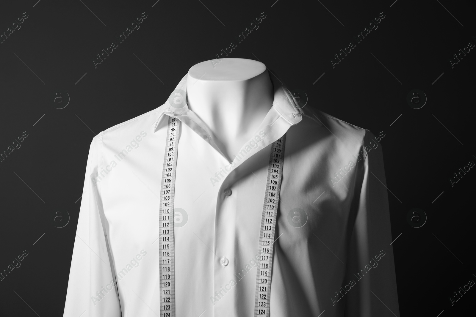 Photo of Male mannequin with white shirt and measuring tape on black background