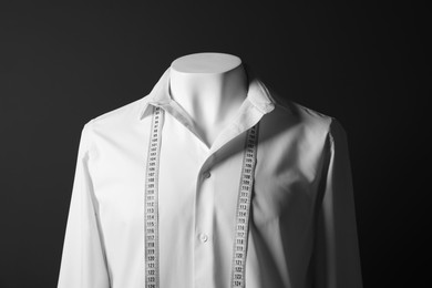 Male mannequin with white shirt and measuring tape on black background