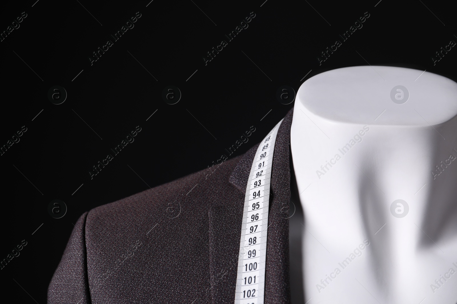 Photo of Male mannequin with jacket and measuring tape on black background, closeup