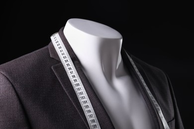 Photo of Male mannequin with jacket and measuring tape on black background, closeup