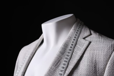 Photo of Male mannequin with grey jacket and measuring tape on black background, closeup