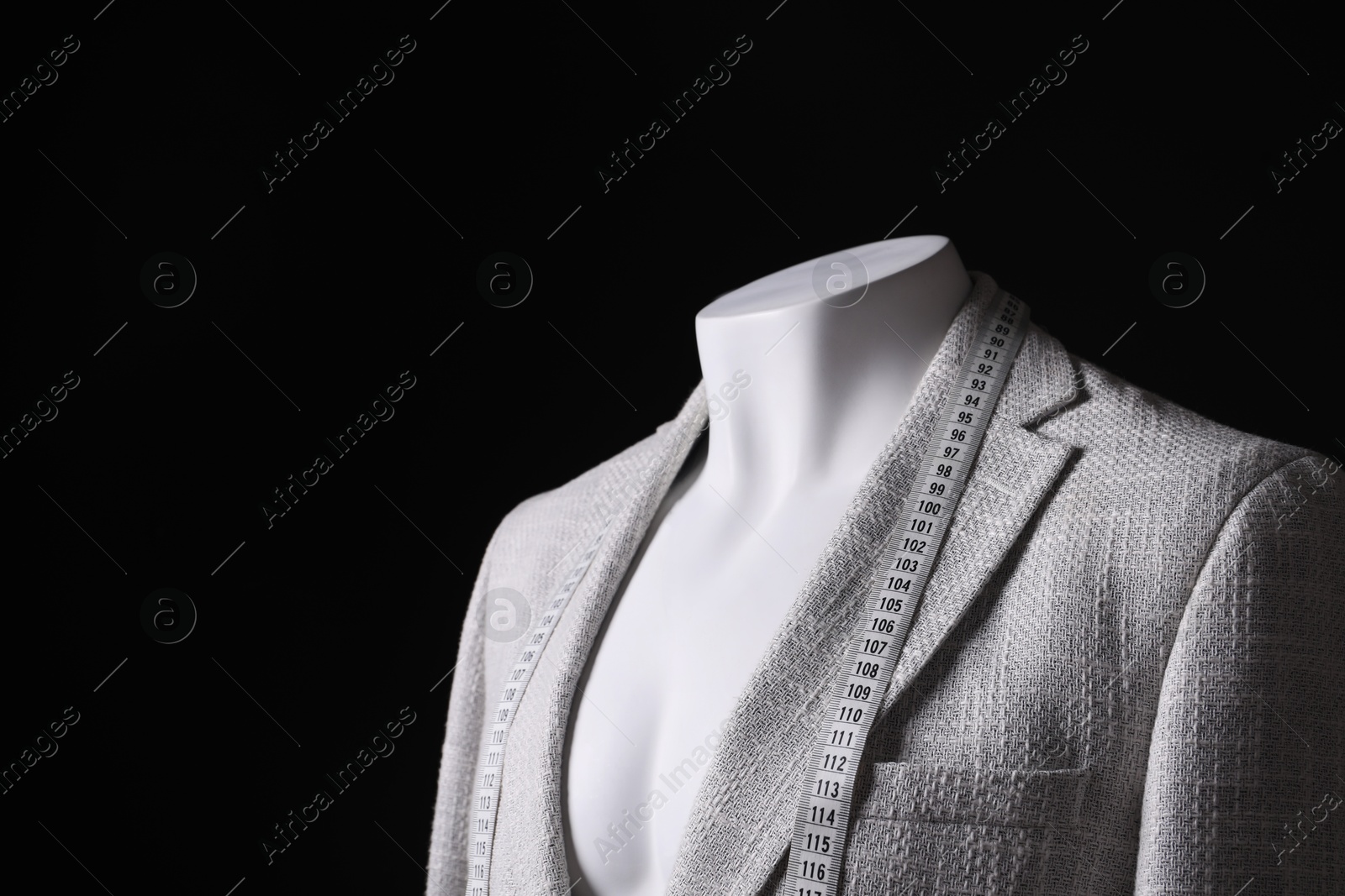 Photo of Male mannequin with grey jacket and measuring tape on black background