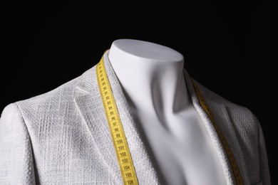 Photo of Male mannequin with grey jacket and measuring tape on black background, closeup