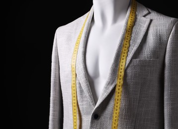 Photo of Male mannequin with grey jacket and measuring tape on black background, closeup