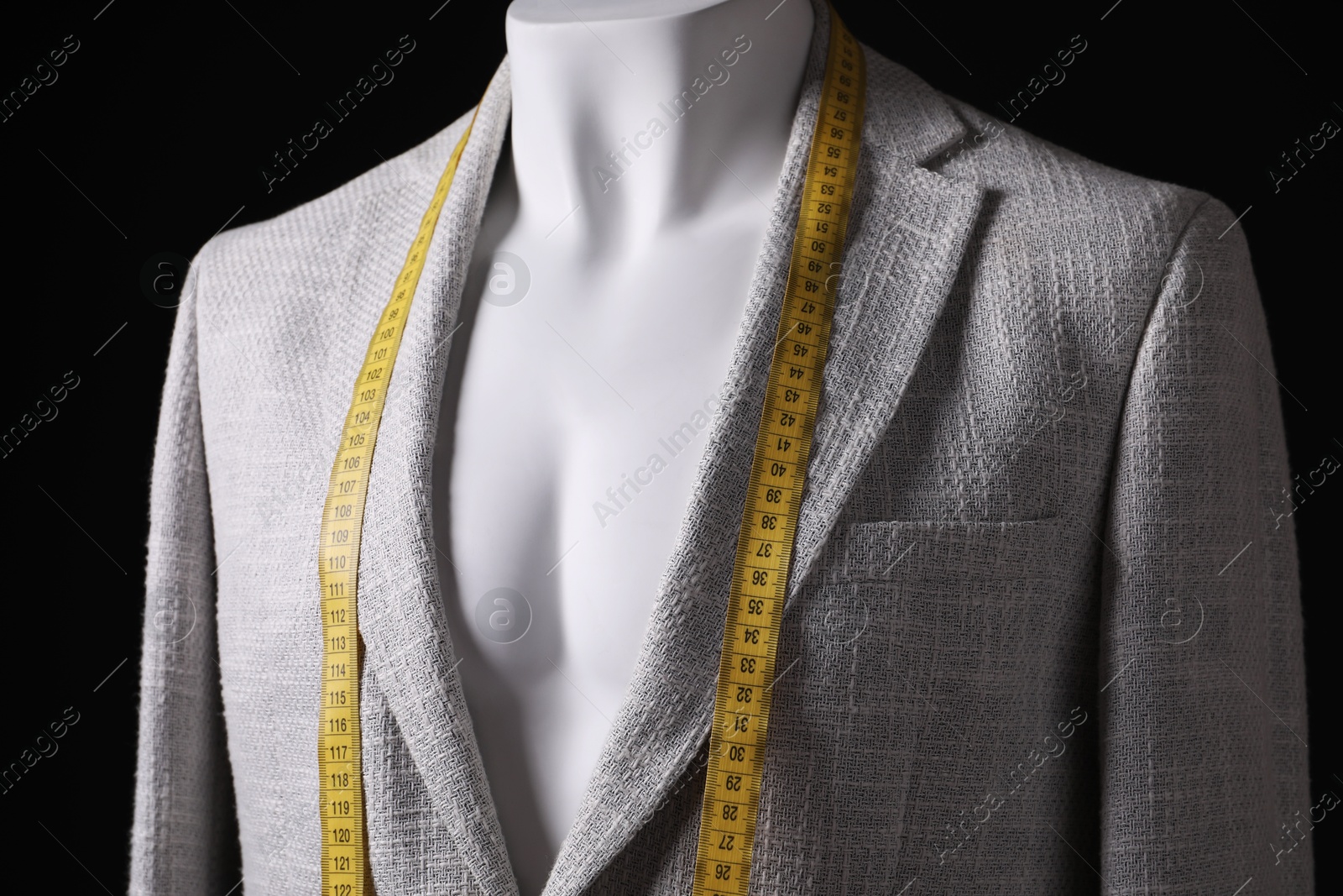 Photo of Male mannequin with grey jacket and measuring tape on black background, closeup