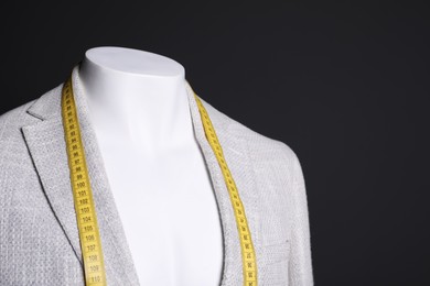 Photo of Male mannequin with grey jacket and measuring tape on black background, closeup