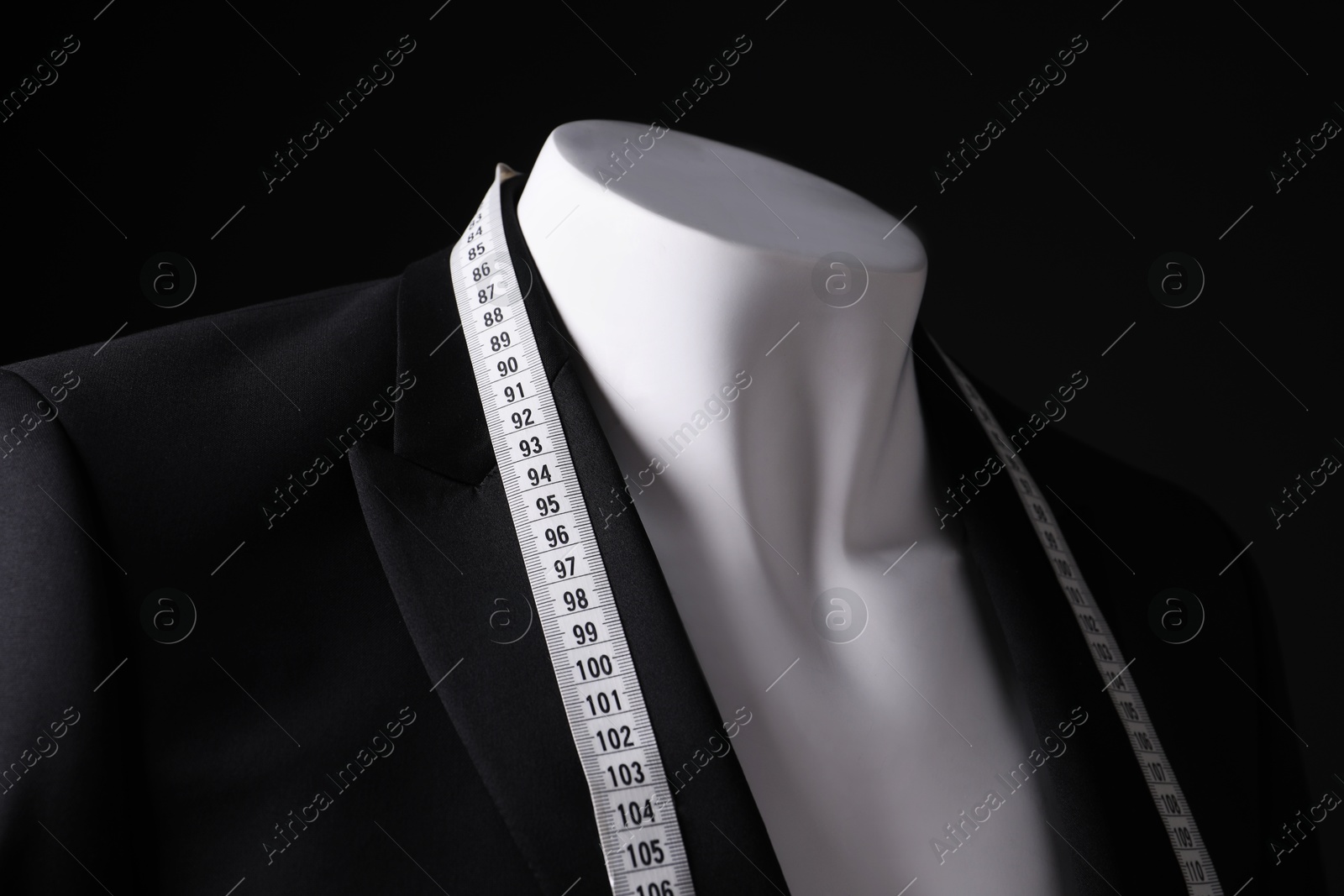 Photo of Male mannequin with jacket and measuring tape on black background, closeup