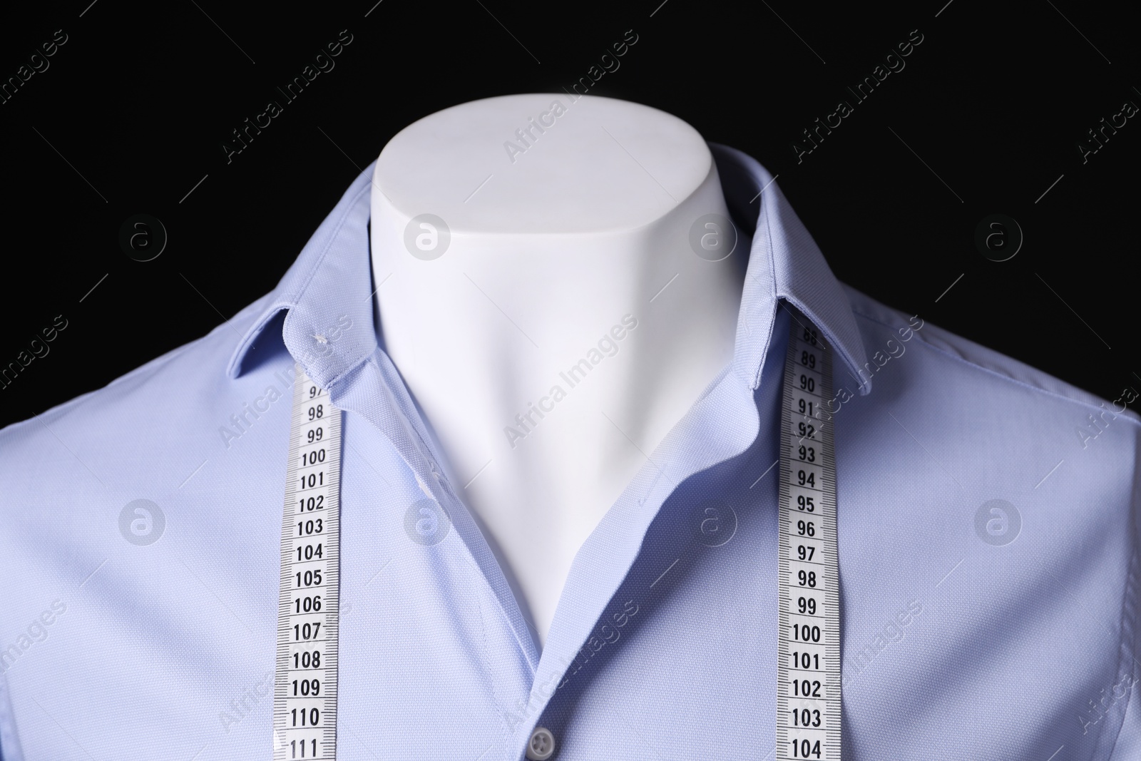 Photo of Male mannequin with light blue shirt and measuring tape on black background, closeup