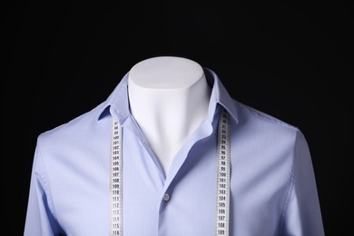 Photo of Male mannequin with light blue shirt and measuring tape on black background, closeup